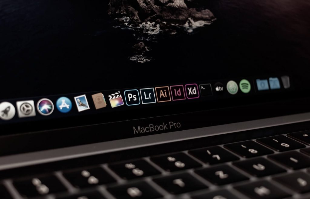 Close-up of a computer screen showing Adobe programs like Photoshop and Lightroom, suggesting the presence of creative editing tools.